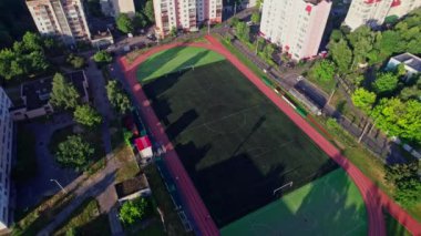 Küçük bir kasabada sokakları olan binaların arkasında futbol sahası boş.