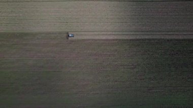 Tarlada çalışan bir traktörün üzerinden uçmak.