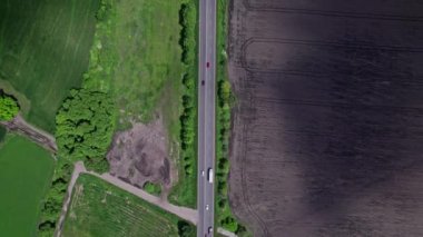 Kırsal alanda yeşil tarlalar boyunca asfalt yolda giden arabalar. Yol havadan görüldü. Hava manzaralı. İHA 'dan ateş etmek