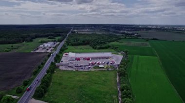 Deponun otoparkından, depolama binasından, yükleme alanından geçen yarı karavan kamyonunun hava görüntüsü.