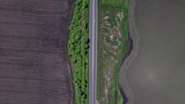 Tarlalar arasındaki asfalt yolda giden arabalar. İHA 'dan yukarıya bak.