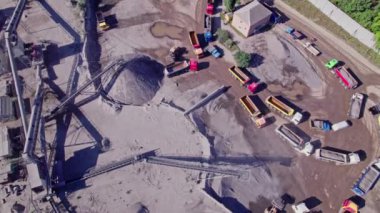 Kazıcı ezilmiş taşı bir kamyona yüklüyor. Çakıl taşlarının çıkarılması için taş ocağı. Üretim, ulaşım