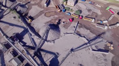 Kazıcı, ezilmiş taş ocağındaki bir çöp kamyonuna ezilmiş taş yüklüyor. Havadan yukarıdan aşağıya görünüm