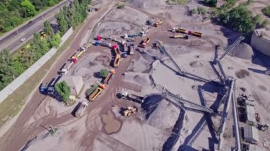 Excavator loading crushed stone into a dump truck in a crushed stone quarry. Aerial top down view
