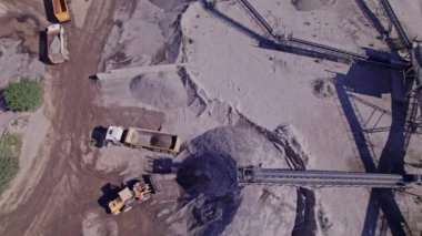 Excavators and tractors load crushed stone and rock into dump trucks. Mining truck transporting stone