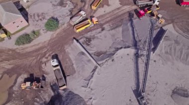 Bir kazıcının, ezilmiş taşı taş ocağındaki bir çöp kamyonuna yüklediği havadan aşağı bakış açısı.