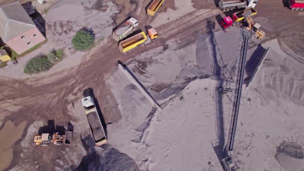 砕石採石場のダンプトラックに砕石をロード掘削機の空中トップダウンビュー — ストック動画