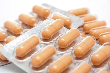 Sarı kapsül paketi beyaz arka planda izole edilmiş. Seçici fokus