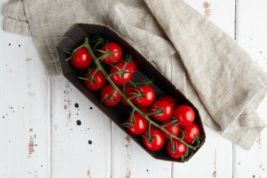 Beyaz ahşap zemin üzerinde taze kırmızı kiraz domatesleri.