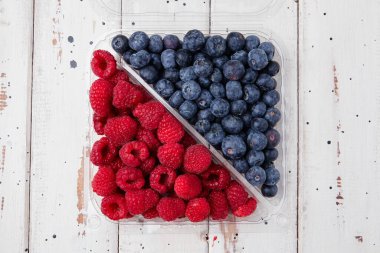 Plastik kutular dolusu taze organik sağlıklı böğürtlen, ahududu, yaban mersini