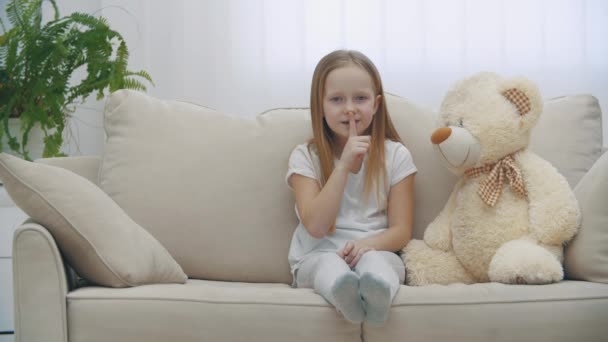 4k-Zeitlupenvideo eines kleinen Mädchens, das ein Zeichen der Stille auf dem Sofa zeigt. — Stockvideo