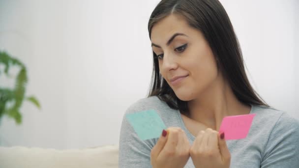 Vidéo ralenti 4k de la femme enceinte tenant des papiers roses et bleus qui signifient le sexe du futur bébé. — Video