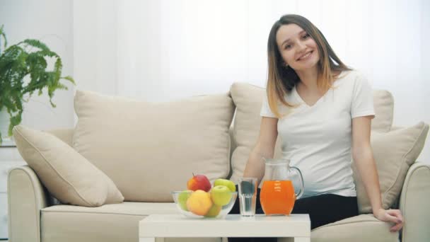 4k відео вагітної жінки сидить на дивані, показуючи великий палець вгору . — стокове відео