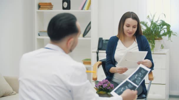 4k wideo ciężarnej kobiety i lekarza pokazujące wyniki USG. — Wideo stockowe