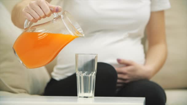 4k beschnittenes Video von schwangerer Frau, die einen Orangensaft ins Glas gießt. — Stockvideo