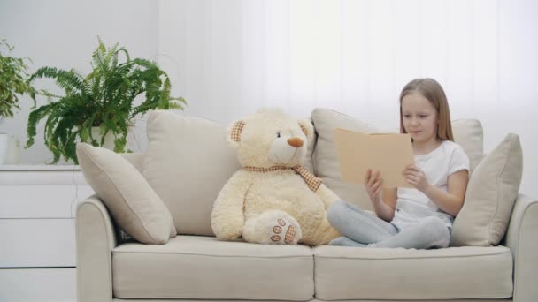 4k-Video eines kleinen Mädchens, das ihrem Teddybär ein Buch vorliest. — Stockvideo