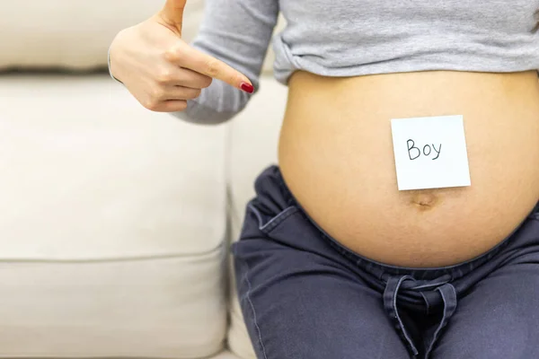 Photo recadrée de l'abdomen féminin avec mot écrit garçon sur le papier. — Photo