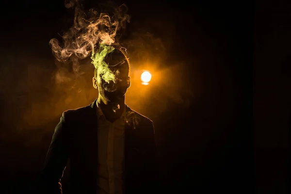 검은 배경 과 황금빛 빛에 담배 라이터를 단 남자의 사진. — 스톡 사진