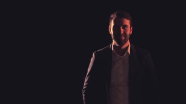 Siyah arka planda siyah takım giyen bir adamın 4K yavaş çekim videosu..