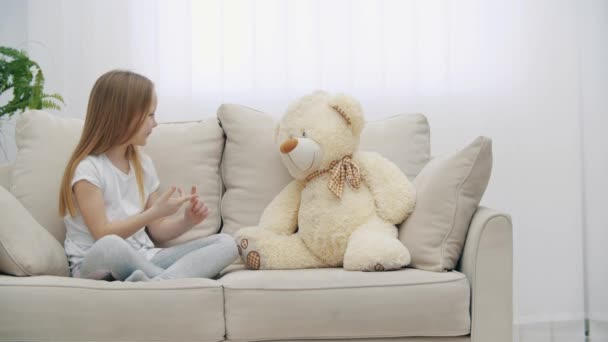 4k lassított felvétel kislányról fehér ruhában, aki Teddy macival beszél. — Stock videók