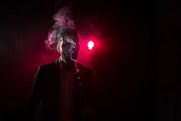 검은 배경 과 핑크 빛에 담배 라이터가 있는 남자의 사진. — 스톡 사진