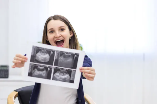 Zdjęcie uśmiechniętej kobiety w ciąży z wynikiem USG. — Zdjęcie stockowe