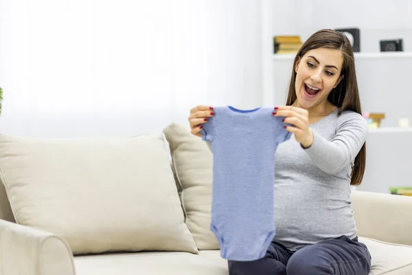Photo de femme enceinte tenant des petits vêtements d'enfant. — Photo
