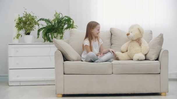 4k video gadis kecil berpakaian putih berbicara dengan boneka beruang. — Stok Video