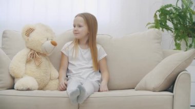 Kanepede oyuncak ayıyla sırlarını paylaşan küçük bir kızın 4k yavaş videosu..