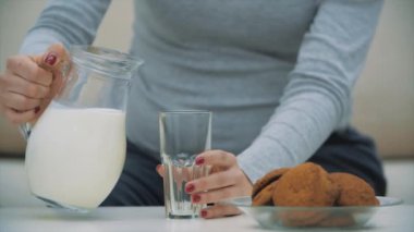 Kadın elinin bir bardak süt ve bisküviyle 4k yavaş çekim videosu..