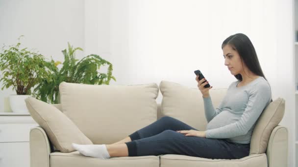 4k видео женщины на диване с помощью телефона. — стоковое видео
