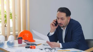 4K videoda hoşnutsuz bir adam telefonla konuşuyor ve gazetelere bakıyor..