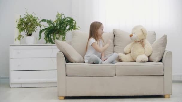 4k video of little girl in white clothes talking to teddy bear. — Stock Video