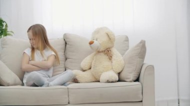 4K video, oyuncak ayının yanında beyaz elbiseli üzgün sarışın kız..