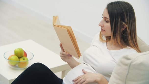 4k video de la mujer embarazada leyendo un libro. — Vídeos de Stock