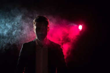Photo of man looking at camera in pink light.