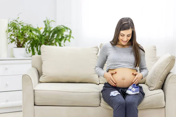 Foto einer schwangeren Frau mit kleinen blauen Männerschuhen. — Stockfoto