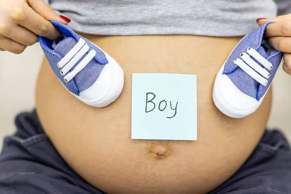 Ausgeschnittenes Foto einer schwangeren Frau mit nacktem Bauch und blauem Papier mit Wortjunge. — Stockfoto