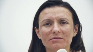 Yüzüne kozmetik süngerle dokunan kötü ciltli bir kadının 4K videosu..