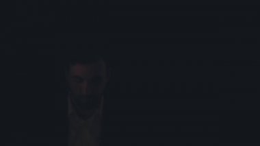 Siyah arka planda siyah takım giyen bir adamın 4K yavaş çekim videosu..