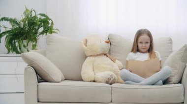 4K yavaş çekim video şaşırmış küçük kız oyuncak ayının yanında elleriyle yüzüne dokunuyor.