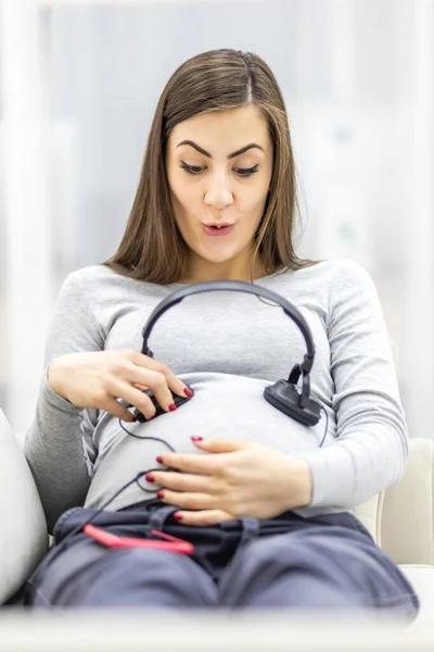 Fotografie překvapené těhotné ženy se sluchátky. — Stock fotografie