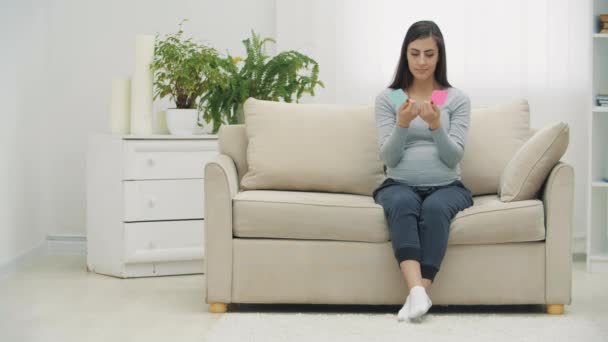 4kビデオの妊娠中の女性を保持ピンクと青の紙これは意味性別の将来の赤ちゃん. — ストック動画