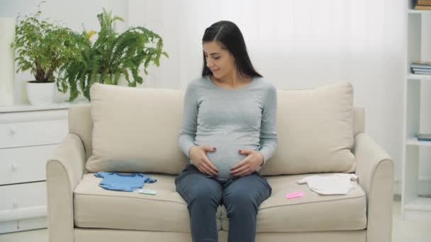 Vidéo 4k de femme enceinte avec des vêtements pour enfants. — Video