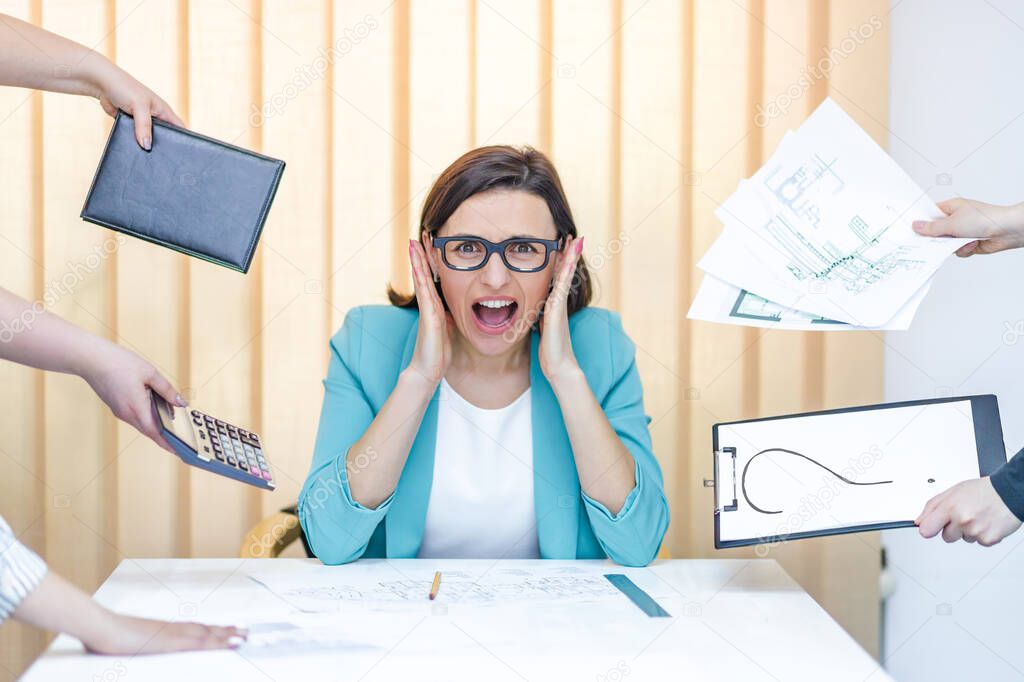 Photo of a businesswoman in blue suit having a lot of work sitting in the office.