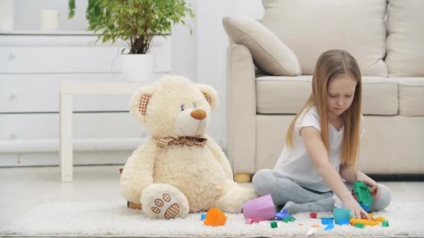 4k video gerakan lambat gadis kecil bermain dengan boneka beruang duduk di lantai. — Stok Video