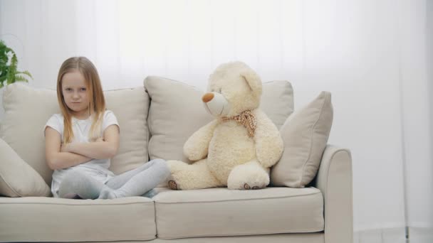 4k video of sad little blond girl in white clothes near teddy bear. — Vídeo de Stock