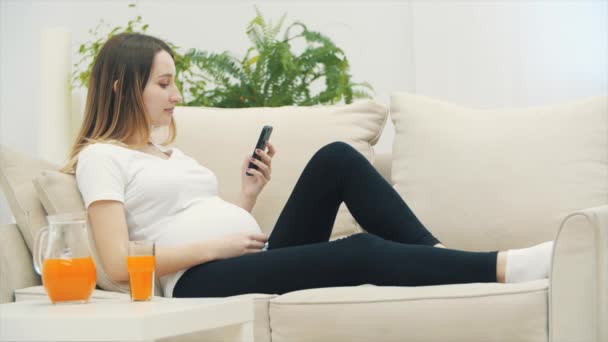 4k video of pregnant woman using phone and drinking juice. — Stock Video