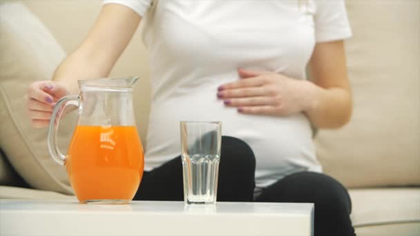 4k beschnittenes Video von schwangerer Frau, die einen Orangensaft ins Glas gießt. — Stockvideo