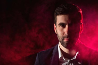 Ayakta duran adamın fotoğrafı ve arka planda pembe ışık..